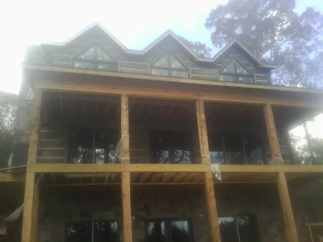 Dormers and porch framing on a large log home under construction — Roof Coating work by our crew in Fort Lee